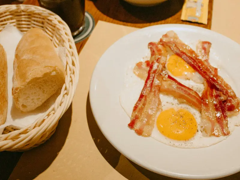 Breakfast plate of bacon, fried eggs and potatoes with toast