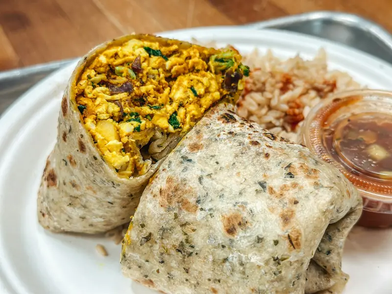 Breakfast burrito filled with scrambled eggs, cut in half on a plate