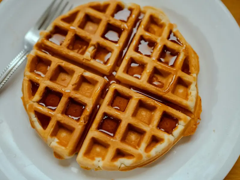 Golden waffle topped with syrup on a white plate